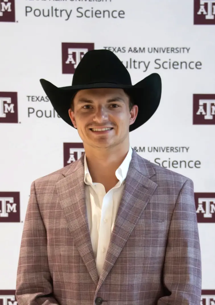 Westen Vardeman wearing a cowboy hat in front of a Texas A&M Poultry Science backdrop